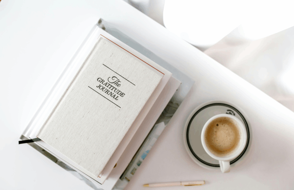 gratitude journal and morning coffee on white desk symbolizing stress management and wellness routines for HPV immune support