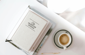 gratitude journal and morning coffee on white desk symbolizing stress management and wellness routines for HPV immune support