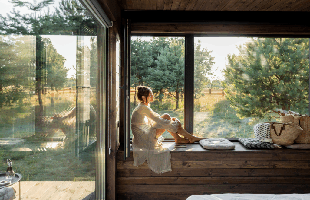 woman sitting in morning sunlight by large window practicing mindfulness and stress regulation for immune health