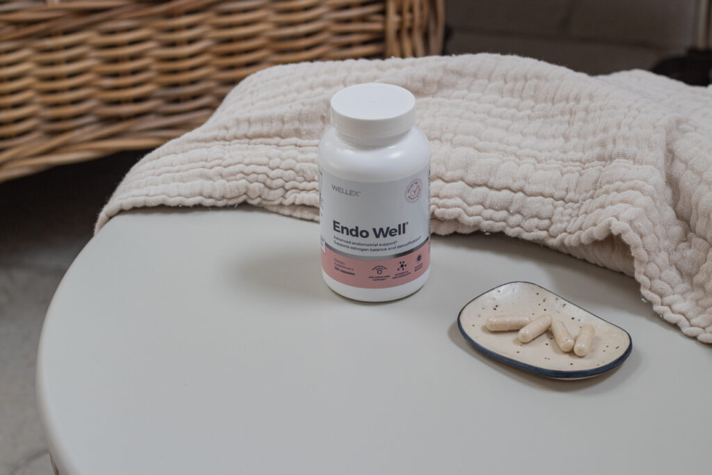 Endo Well supplement by Wellex placed on a soft neutral surface beside capsules, representing support for estrogen metabolism and hormonal balance.