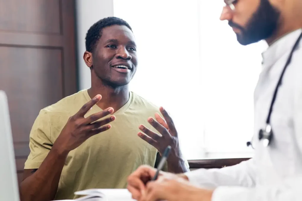 A healthcare provider speaking with a male patient during a consultation.