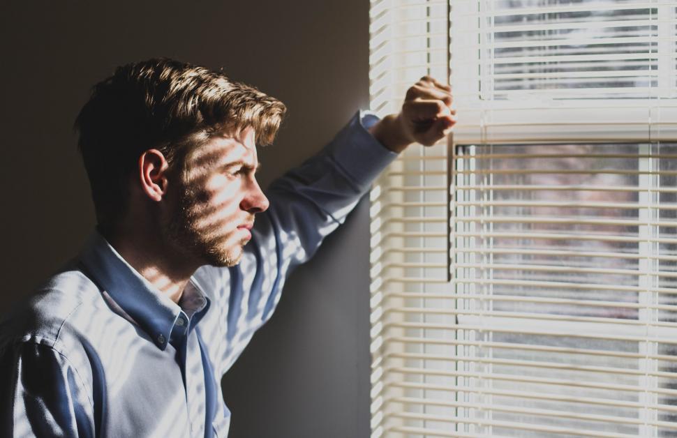 A man sitting by a window in natural light, reflecting and reading.