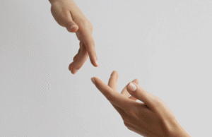 Two hands reaching toward each other against a neutral background, fingers slightly extended but not yet touching.